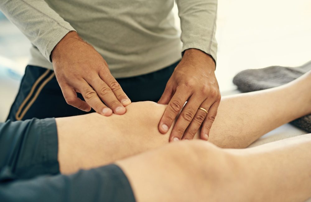 Cropped shot of an unidentifiable physiotherapist massaging his patients knee.